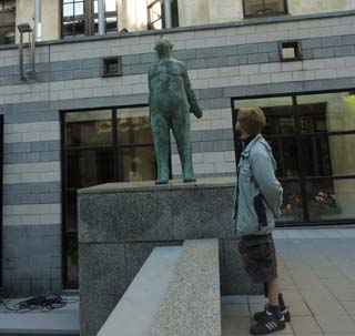 Un bonhomme qui regarde en l'air une statue qui regarde en l'air.